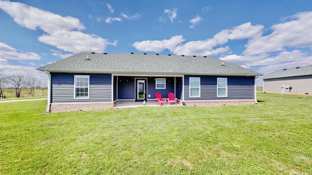 rear view of property featuring a shingled roof, a patio area, and a yard
