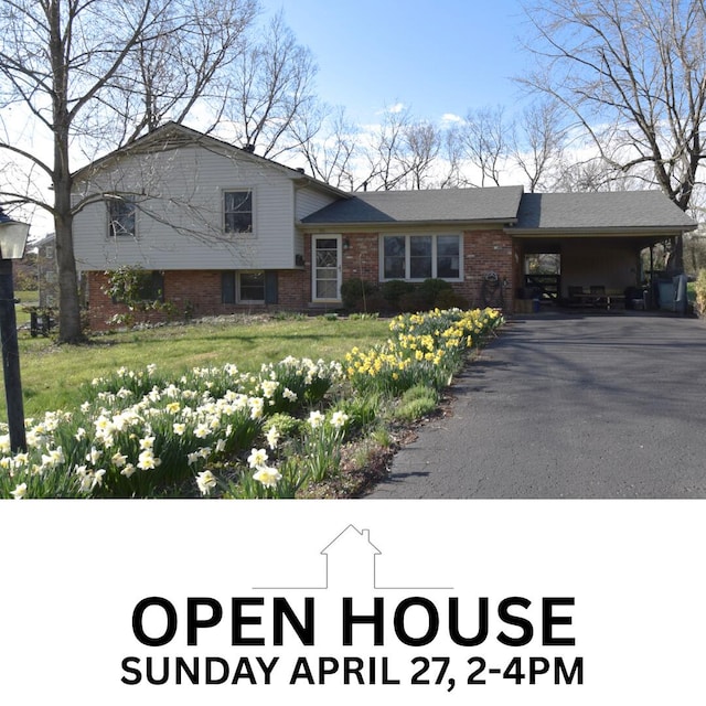 tri-level home featuring driveway, brick siding, and an attached carport