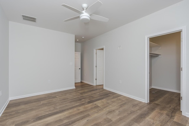 unfurnished bedroom featuring baseboards, wood finished floors, visible vents, and a walk in closet