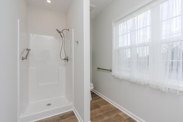 bathroom featuring wood finished floors, visible vents, toilet, baseboards, and a shower