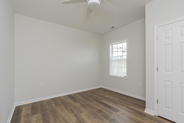 empty room with baseboards, visible vents, a ceiling fan, and dark wood-style floors