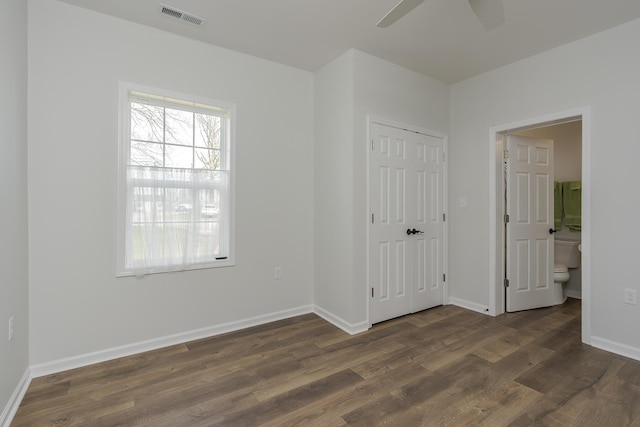 unfurnished bedroom featuring baseboards, dark wood-type flooring, and visible vents