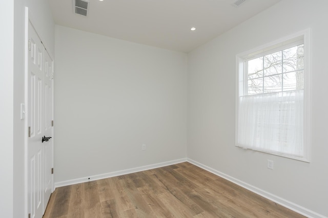 unfurnished room featuring recessed lighting, wood finished floors, visible vents, and baseboards