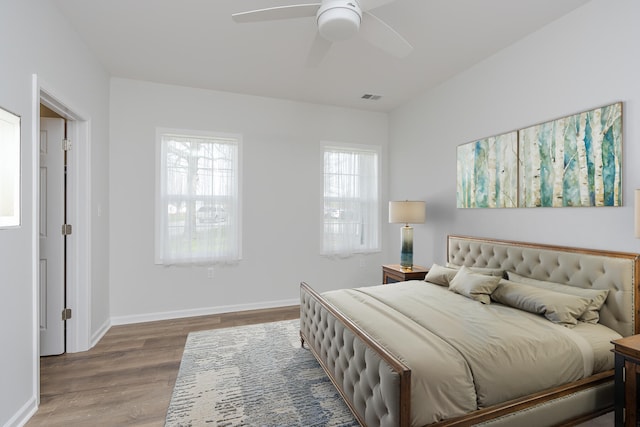bedroom featuring visible vents, baseboards, wood finished floors, and ceiling fan