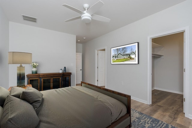 bedroom with baseboards, visible vents, a spacious closet, wood finished floors, and ceiling fan