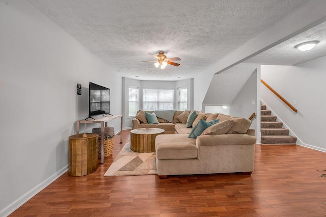 living room with baseboards, stairway, a textured ceiling, a ceiling fan, and wood finished floors