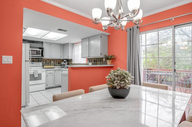 kitchen with a chandelier, white appliances, light tile patterned floors, crown molding, and decorative backsplash