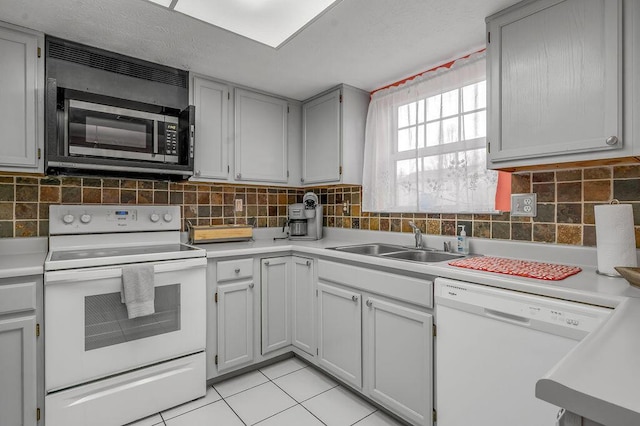 kitchen with tasteful backsplash, white appliances, light countertops, and a sink