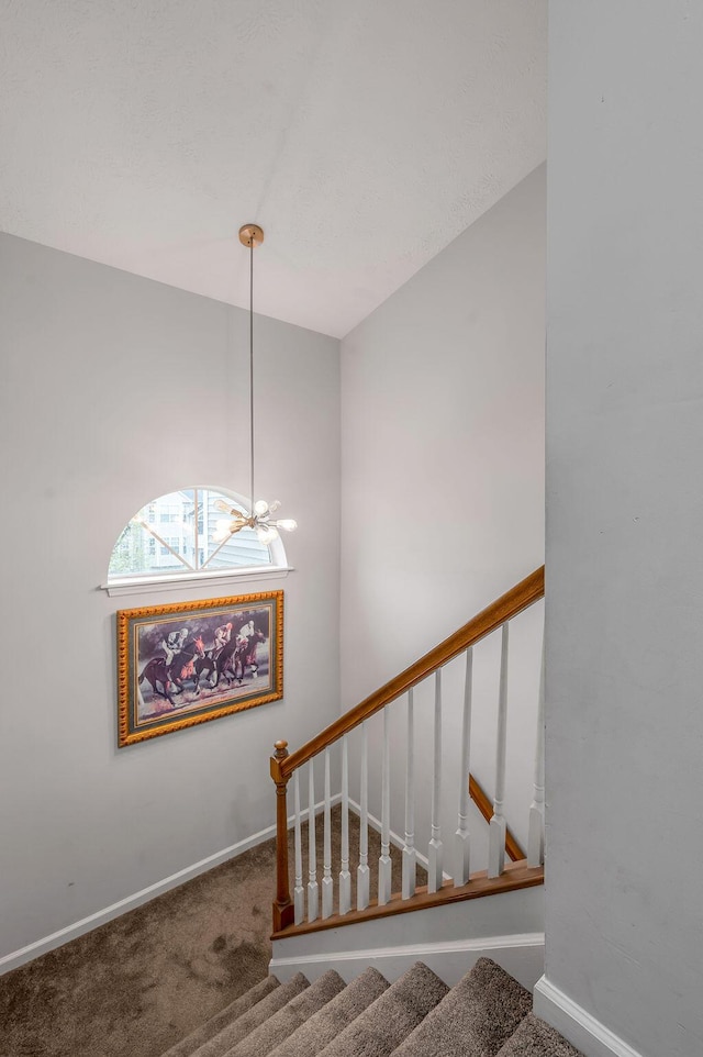 stairs featuring a notable chandelier, baseboards, and carpet floors