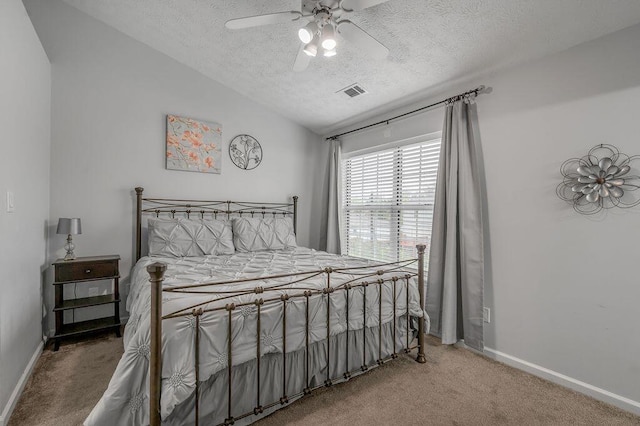 carpeted bedroom with ceiling fan, a textured ceiling, vaulted ceiling, visible vents, and baseboards