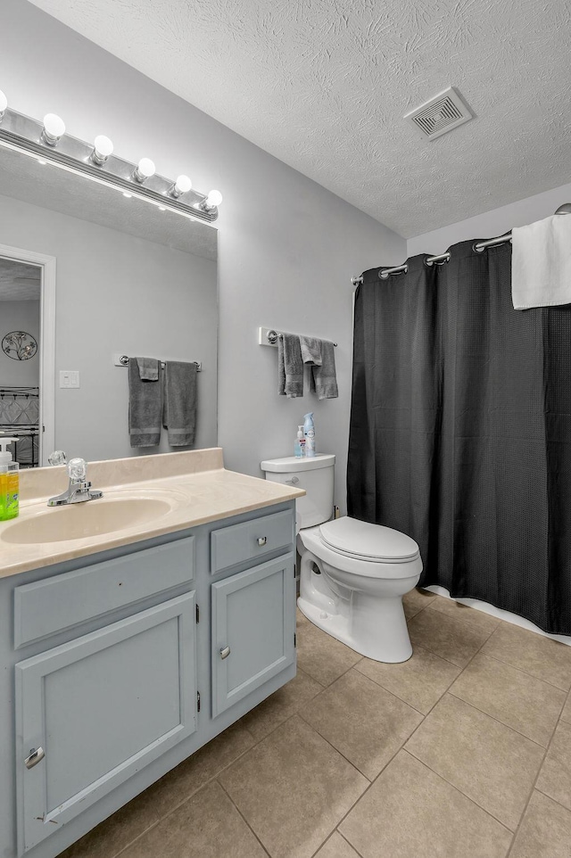 full bath featuring a textured ceiling, vanity, tile patterned flooring, visible vents, and toilet