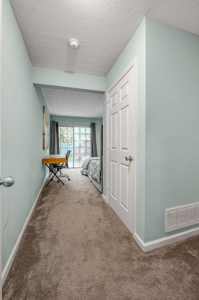 hallway featuring carpet flooring, visible vents, and baseboards