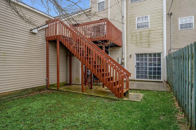 rear view of property with a yard, fence, and stairway