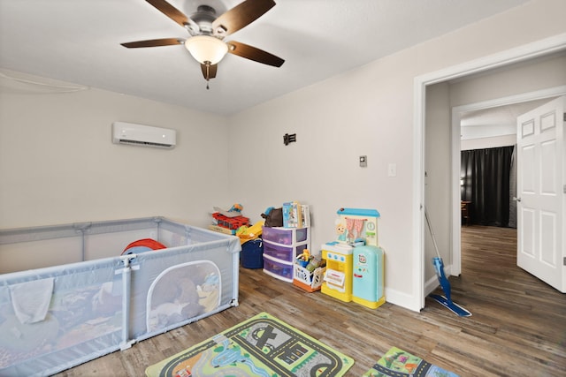 playroom featuring wood finished floors, ceiling fan, baseboards, and an AC wall unit