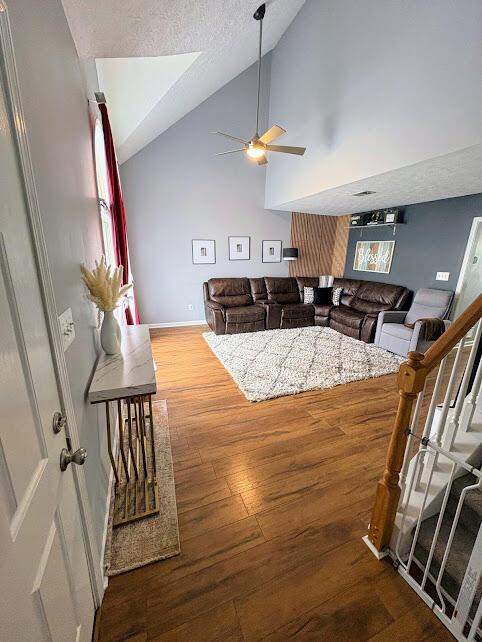 living room featuring lofted ceiling, a ceiling fan, baseboards, and wood finished floors