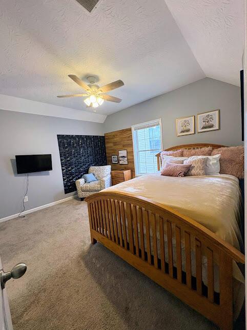 bedroom featuring vaulted ceiling, a ceiling fan, carpet floors, baseboards, and a textured ceiling