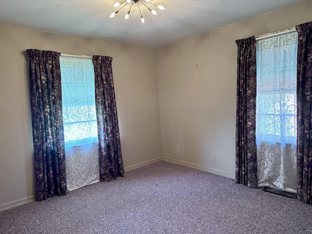 unfurnished room with a wealth of natural light, carpet flooring, a chandelier, and baseboards