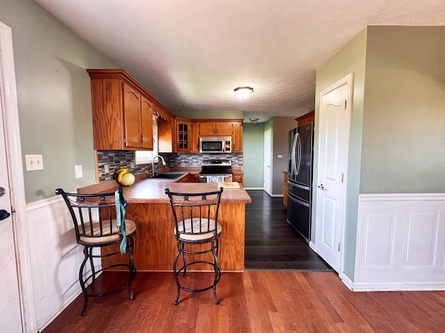 305 Saddle Wood Ct, Berea, KY 40403 - kitchen featuring glass insert cabinets, appliances with stainless steel finishes, brown cabinets, backsplash, and a peninsula