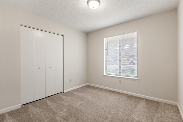 unfurnished bedroom featuring baseboards, carpet, a closet, and a textured ceiling