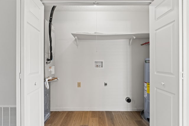 clothes washing area with light wood-style floors, hookup for a washing machine, visible vents, water heater, and hookup for an electric dryer