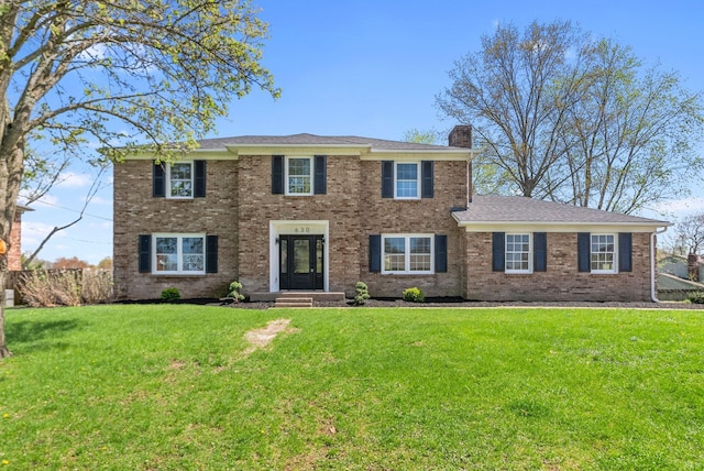 colonial house with a chimney, a front lawn, and brick siding
