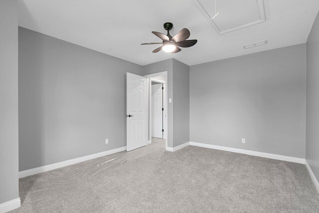 unfurnished room featuring carpet, a ceiling fan, visible vents, attic access, and baseboards