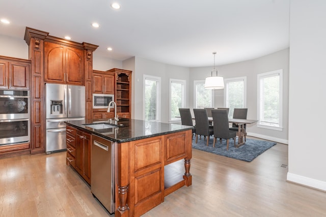 kitchen featuring dark stone countertops, a sink, appliances with stainless steel finishes, recessed lighting, and light wood finished floors