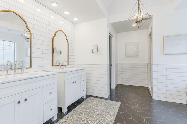 bathroom with two vanities, a sink, tile walls, tile patterned floors, and a notable chandelier