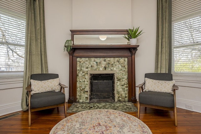 sitting room with baseboards, wood finished floors, a fireplace, and visible vents