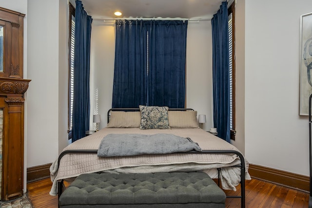 bedroom featuring wood-type flooring, multiple windows, and baseboards