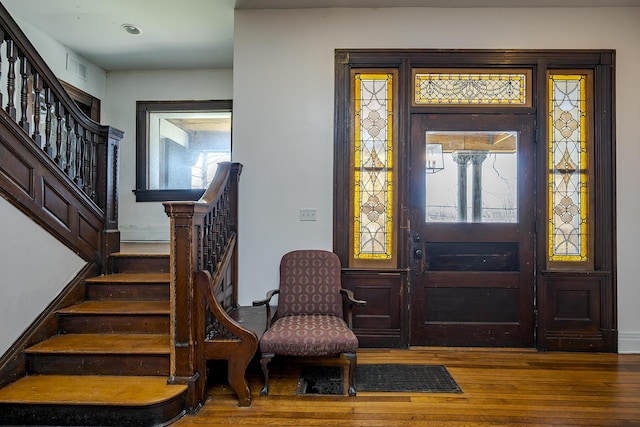 entrance foyer featuring wood finished floors, a healthy amount of sunlight, visible vents, and stairway