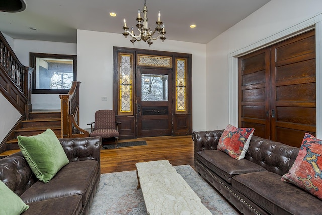 living area with recessed lighting, stairway, an inviting chandelier, and wood finished floors