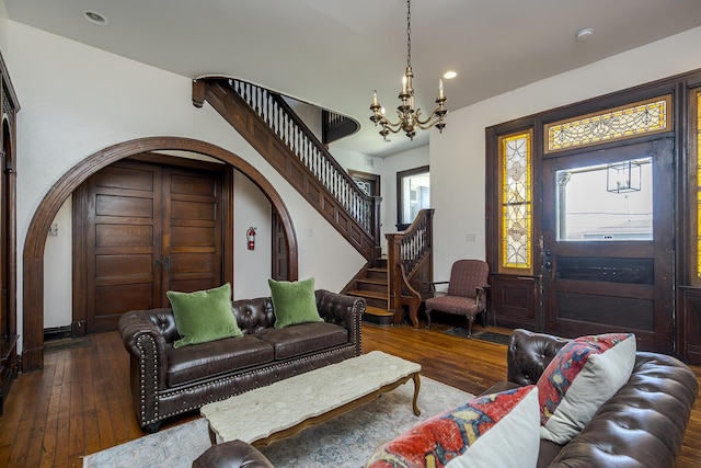 living area with an inviting chandelier, arched walkways, recessed lighting, stairway, and wood-type flooring