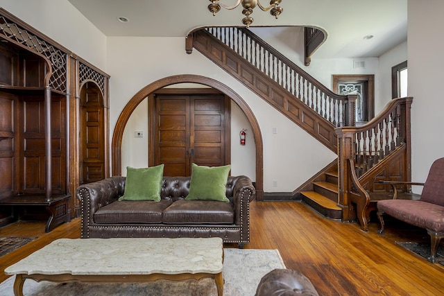 living area featuring recessed lighting, stairs, visible vents, hardwood / wood-style floors, and arched walkways