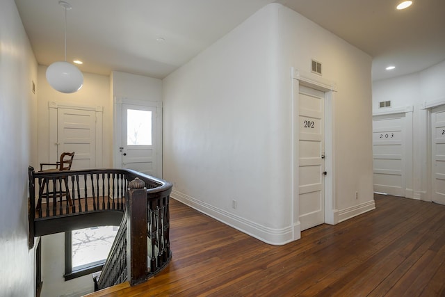 corridor featuring wood-type flooring, visible vents, and baseboards
