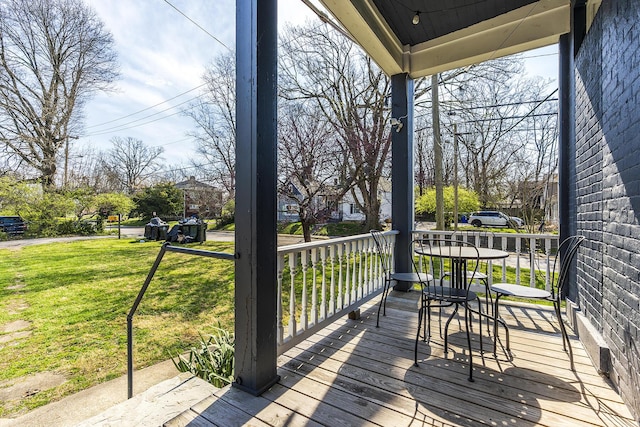 wooden terrace featuring a porch and a yard