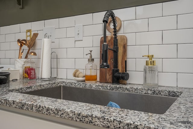 details featuring a sink, decorative backsplash, and stone countertops
