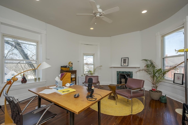 office space featuring baseboards, a fireplace, recessed lighting, a ceiling fan, and hardwood / wood-style flooring