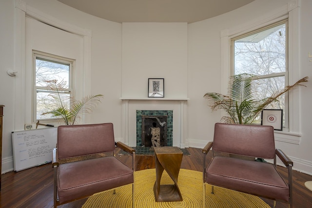 sitting room featuring a tiled fireplace, baseboards, plenty of natural light, and wood finished floors