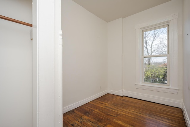 unfurnished room featuring baseboards and dark wood finished floors