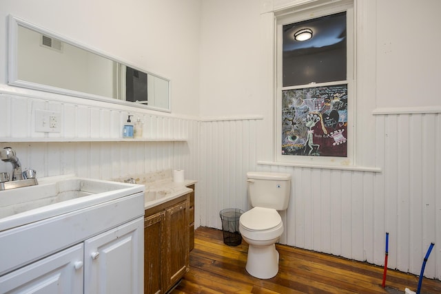 bathroom featuring vanity, visible vents, a wainscoted wall, toilet, and hardwood / wood-style floors