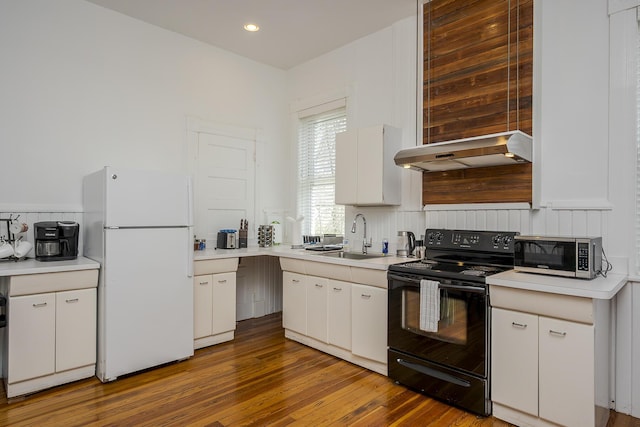 kitchen with freestanding refrigerator, under cabinet range hood, stainless steel microwave, a sink, and black / electric stove