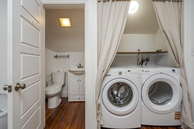 clothes washing area featuring dark wood-style flooring, washer and clothes dryer, laundry area, and a sink