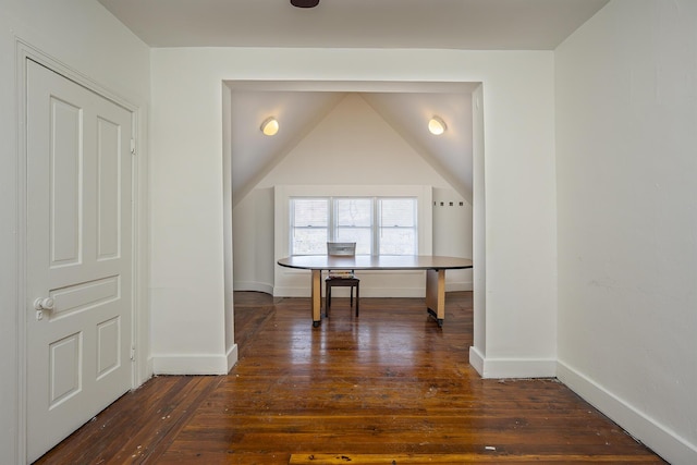 interior space with baseboards, vaulted ceiling, and dark wood finished floors
