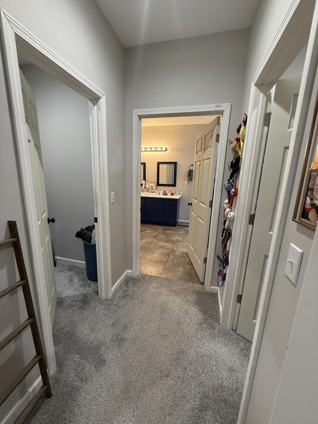hallway featuring light colored carpet and baseboards