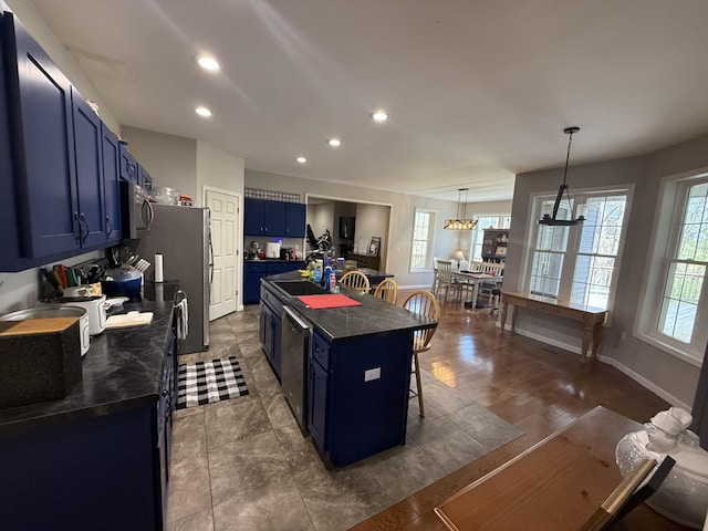 kitchen featuring stainless steel microwave, a center island, blue cabinetry, black dishwasher, and dark countertops