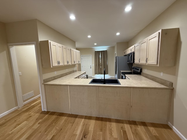 kitchen featuring light wood-type flooring, light countertops, a sink, and appliances with stainless steel finishes