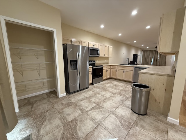 kitchen featuring recessed lighting, light countertops, appliances with stainless steel finishes, a sink, and light brown cabinetry
