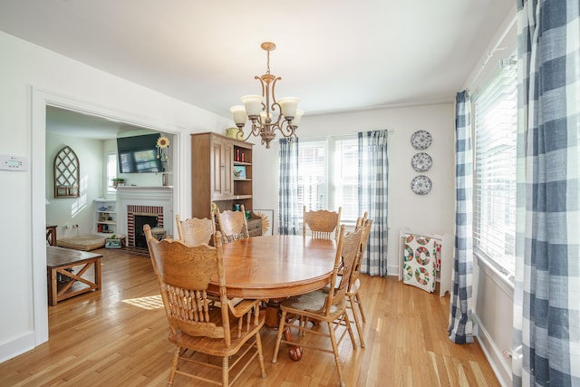 5 Bath Ave, Owingsville, KY 40360 - dining space with light wood finished floors, an inviting chandelier, baseboards, and a brick fireplace