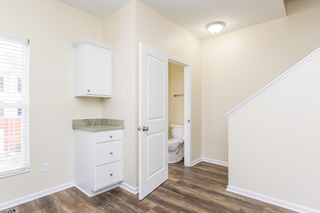 interior space with dark wood-type flooring, visible vents, and baseboards